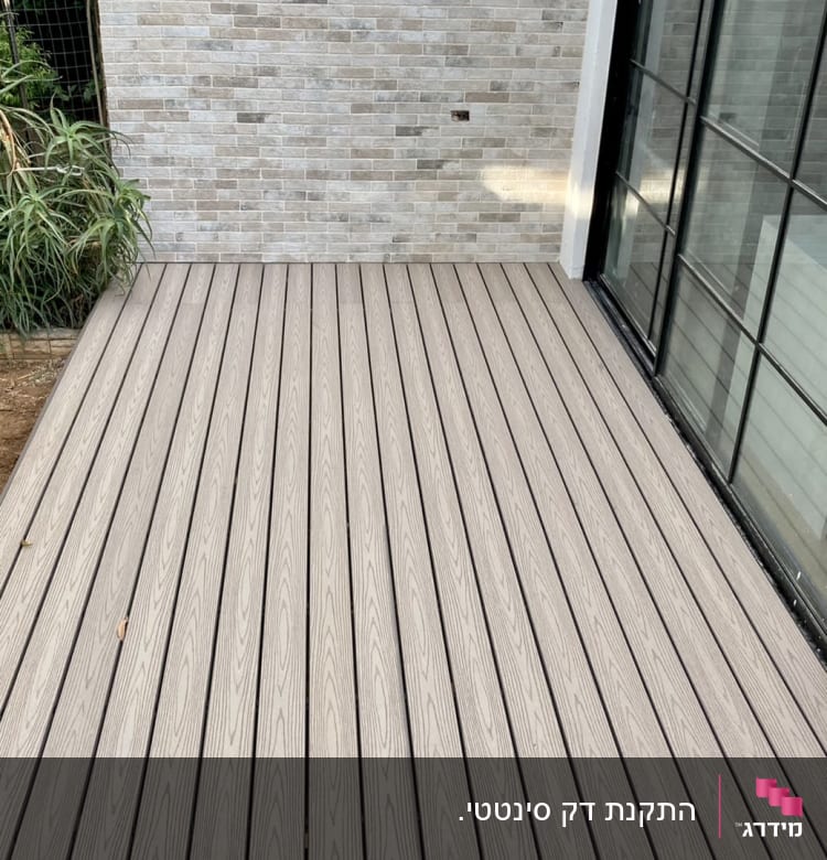 דק עץ בהיר ליד קיר לבנים אפור